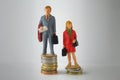 Stack pile of coins with miniature man and woman. GenderÃÂ payÃÂ discriminationÃÂ concept.ÃÂ Wage disparity between men and women